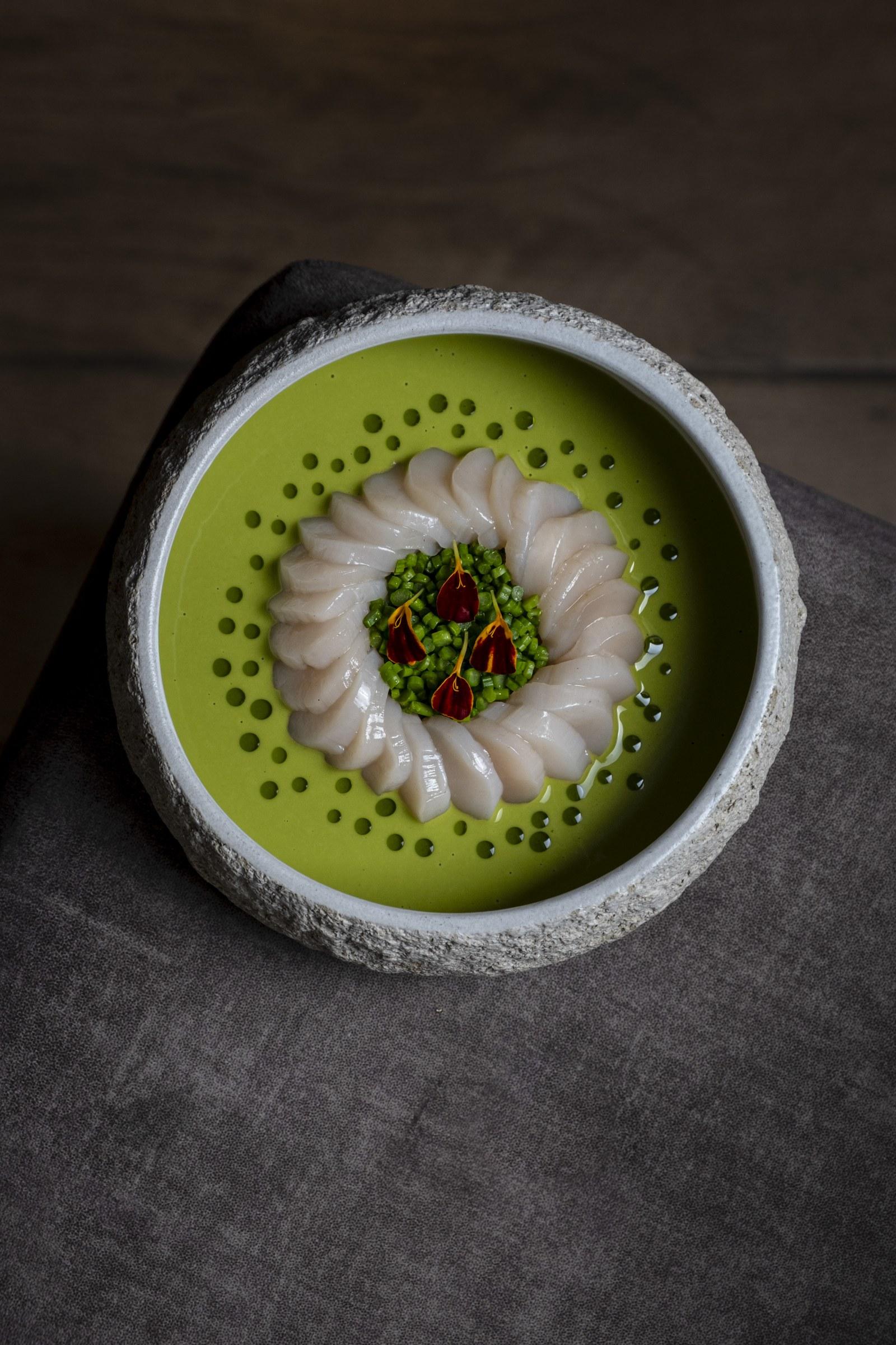 Láminas de pescado sobre salsa verde en bowl de piedra